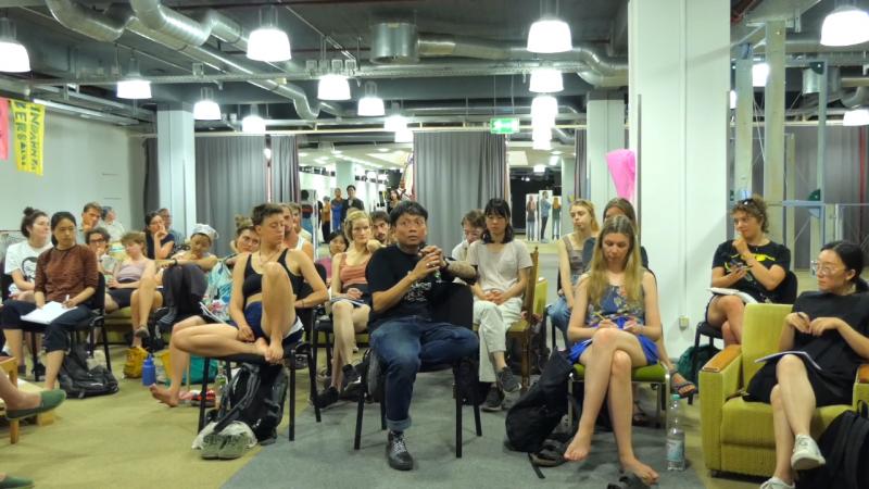 Reza Afisina from ruangrupa speaking to students and professors from LAPS, Kassel Universitet and Szczecin Art Academy at the documenta fifteen, Kassel in August 2022