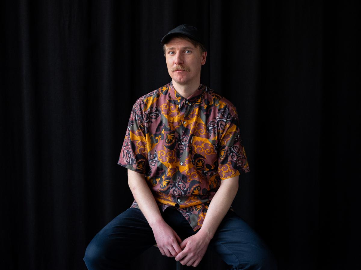 Olli Valkola istuu, poseeraa kameralle